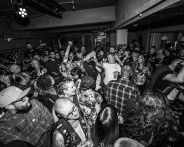 Black and white image of a crowd packed into a small underground music venue