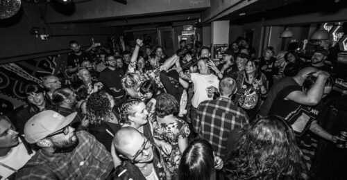 Black and white image of a crowd packed into a small underground music venue