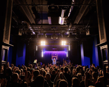 A crowded venue (Band on the Wall) with a performer on stage